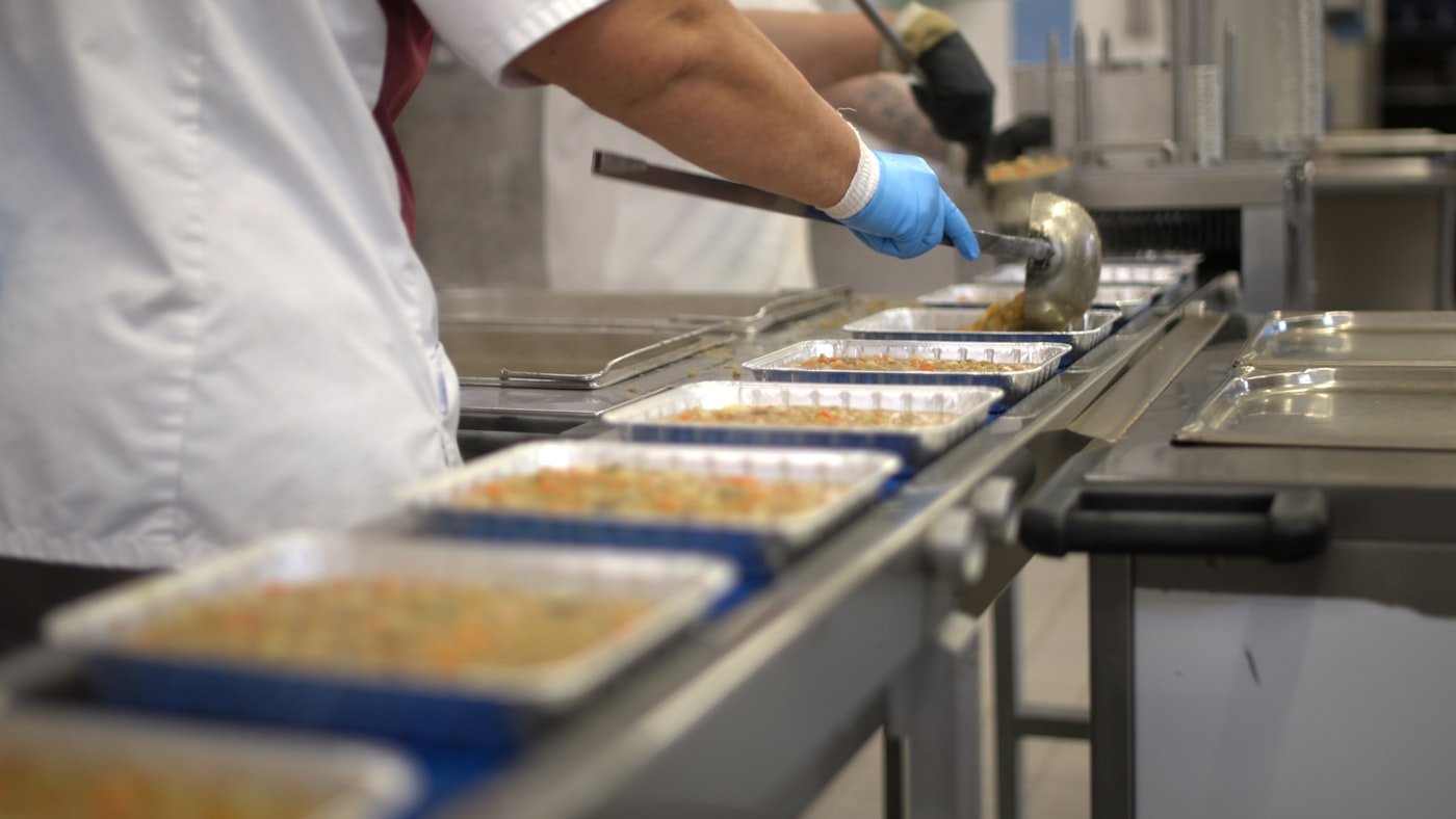 Workers portioning food on a commissary production line