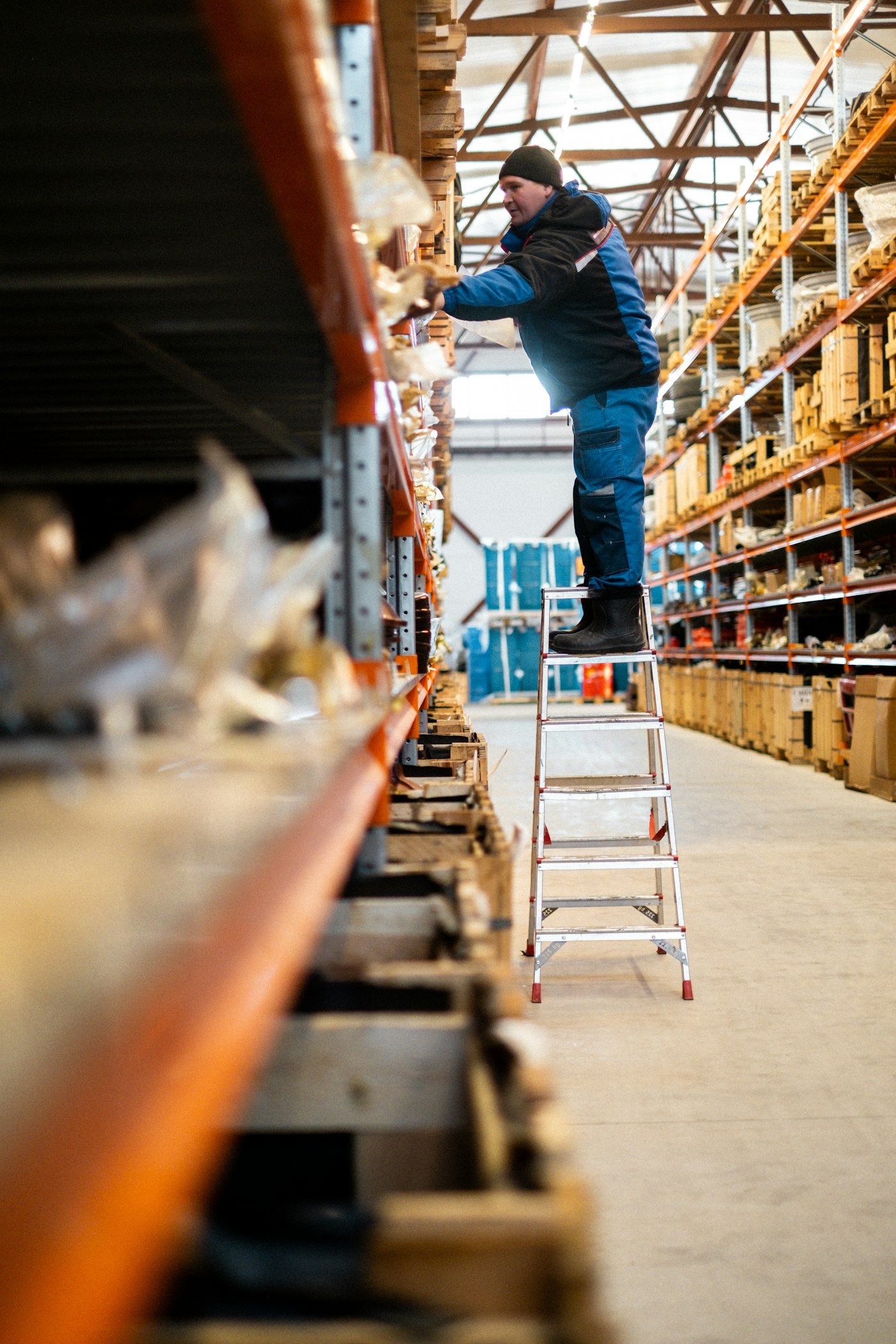 Team member on a ladder picking stock from warehouse shelving